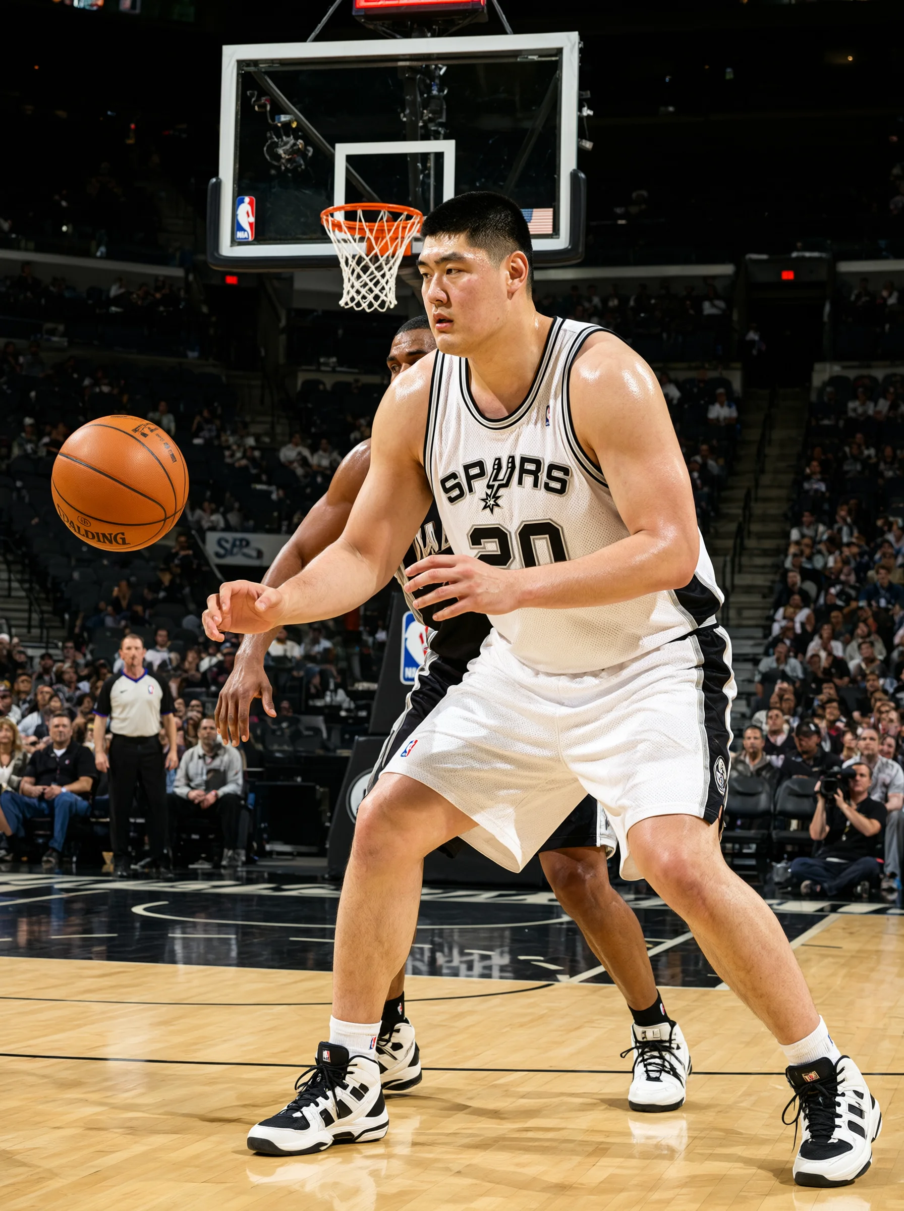 篮球比赛中，一名身穿白色马刺（SPURS）球衣的高大球员在篮下屈膝张手，准备接住左侧飞来的篮球，身后一名黑衣球员贴身卡位；背景为篮板、篮筐与看台观众。